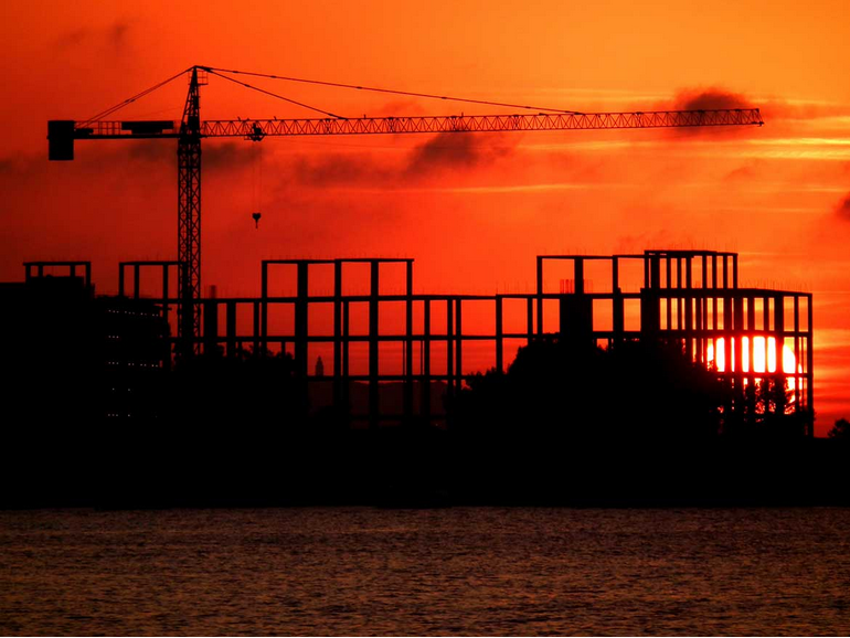 Construction cranes and structural frames at sunset